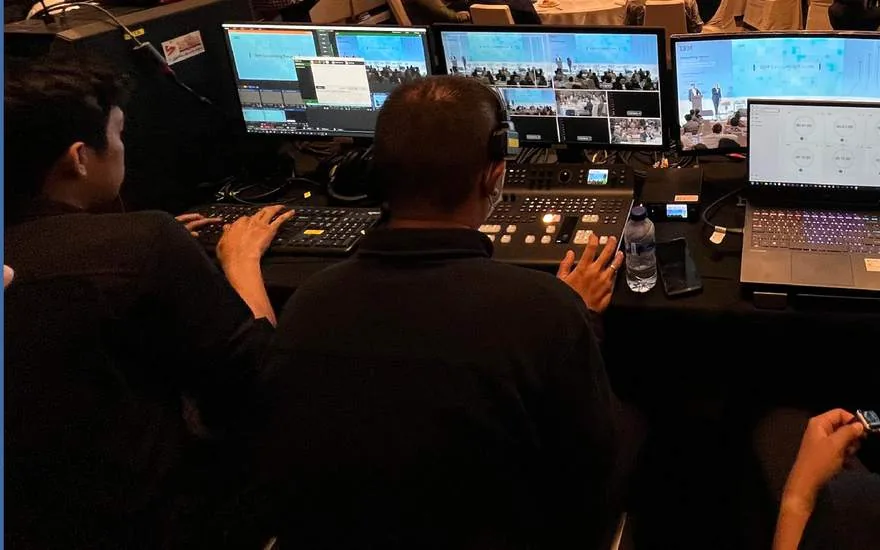 Kru broadcast mengawasi monitor pada acara korporat hybrid.